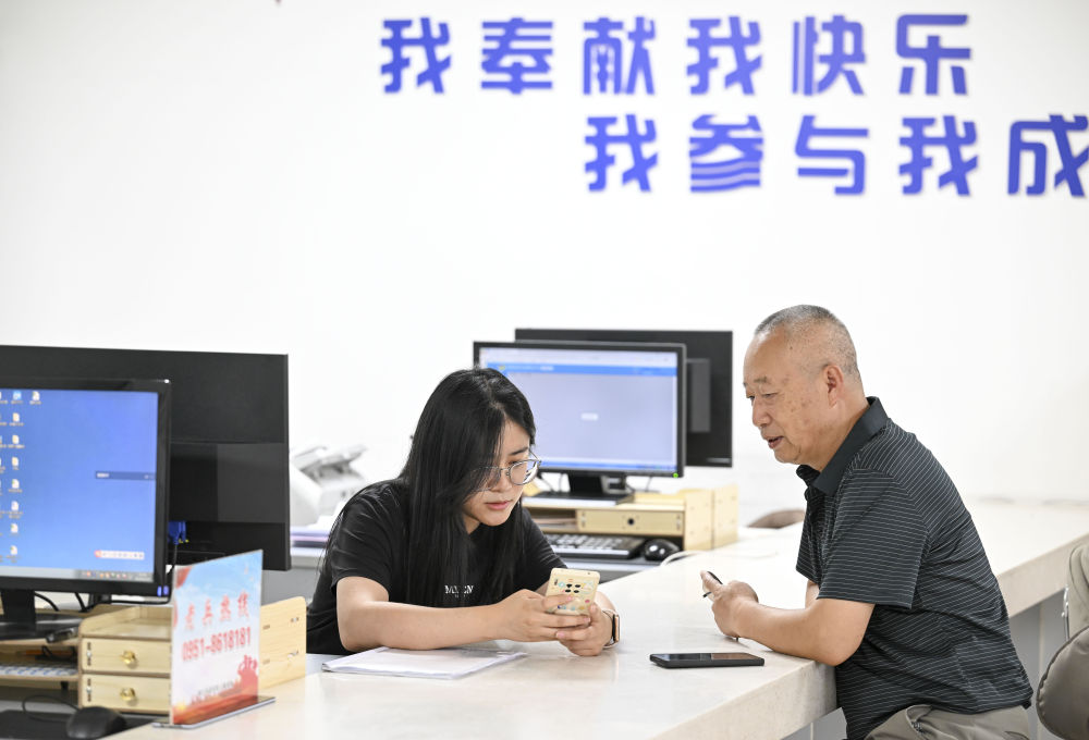 2024年6月20日，在寧夏銀川市金鳳區長城花園社區黨群服務中心，工作人員幫助居民辦理業務。圖片來源 新華社
